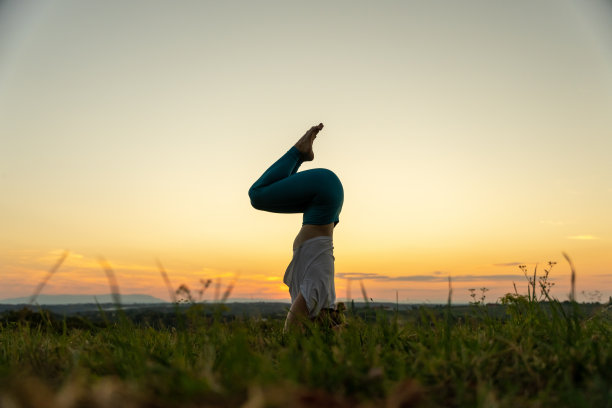 一名女子在草地上练习鹰路荼头倒立图片下载