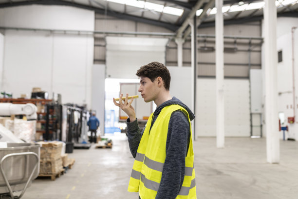 在一家工厂里，年轻的白人工人通过语音信息完成工作图片下载