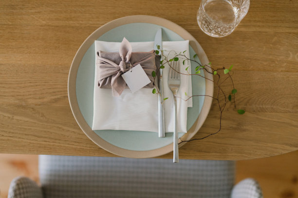 婚宴的餐桌布置。有美丽的花朵和绿色植物的花卉作品，蜡烛，装饰好的桌子上的摆设和盘子。图片下载