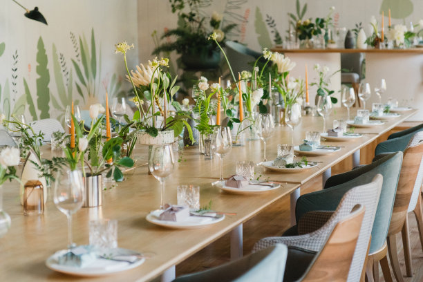 婚宴的餐桌布置。有美丽的花朵和绿色植物的花卉作品，蜡烛，装饰好的桌子上的摆设和盘子。图片下载