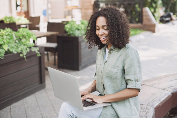 快乐的女人在城市里使用笔记本电脑图片下载