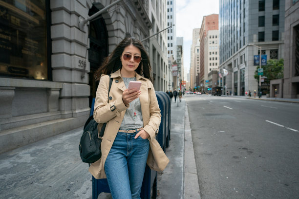美国加州旧金山，一名台湾女商人戴着墨镜，用手机站在邮筒旁等待客户图片下载