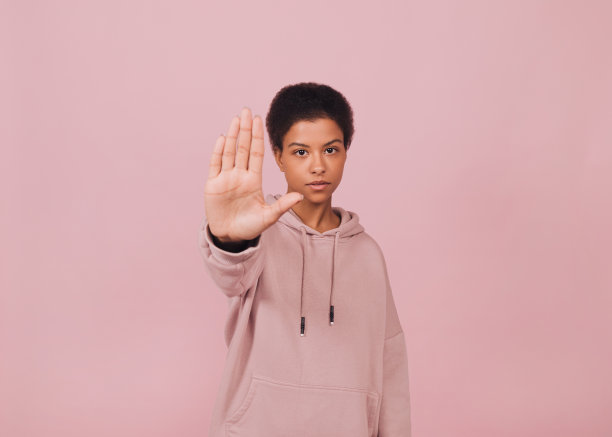 年轻美丽的爆炸头女人做停止标志。图片下载