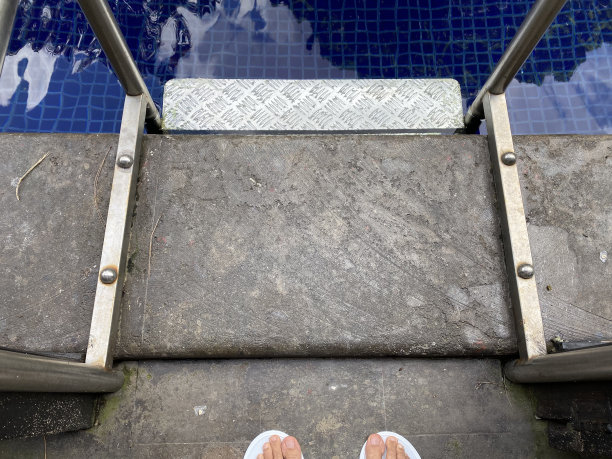 游泳池的楼梯和脚的人享受它图片下载