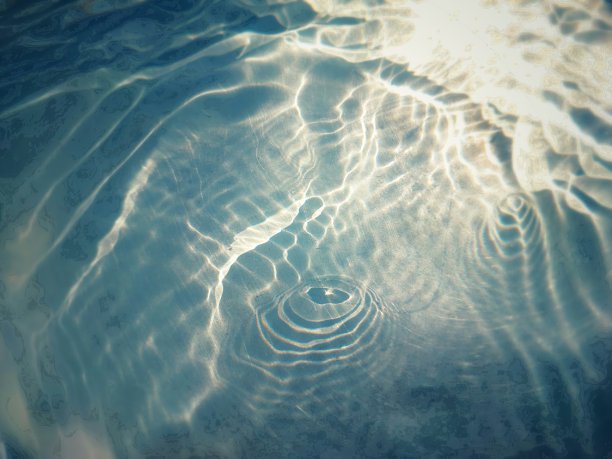 离焦模糊透明蓝色颜色清晰平静的水面纹理与飞溅和气泡。潮流抽象的自然背景。水波在阳光下复制空间。蓝色水彩闪光图片下载