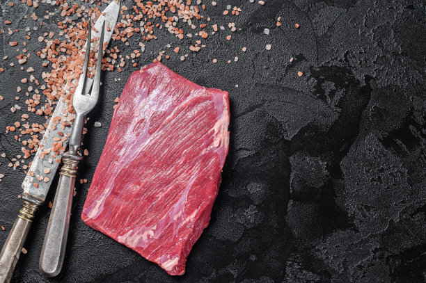 生的在餐桌上的生的牛腩肉。黑色背景。前视图。本空间图片下载