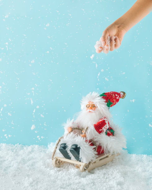 2023. 最小的圣诞冬季风景与孩子的手撒雪在圣诞老人在他的雪橇。孤立的雪粉蓝色背景。圣诞节庆祝概念。新年祝福或礼品卡。图片下载