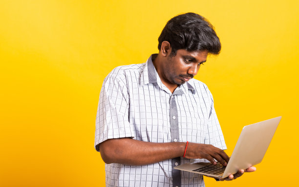 黑人男子微笑着站着，穿着衬衫，拿着笔记本电脑打字图片下载