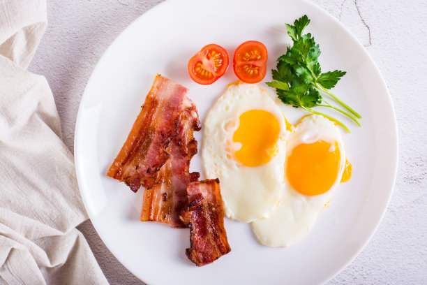 煎蛋和培根，西红柿和欧芹放在盘子里。自制的早餐。前视图。特写镜头图片下载