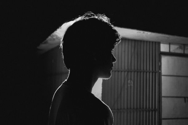 一个南亚男孩站在灯泡前的灰度照片图片下载