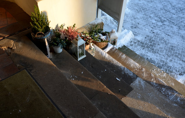 餐厅入口处的装饰。桌子上有塑料花和金属灯笼。有石南花的花盆。草坪和石头人行道，楼梯，天使，雪，圣诞节图片下载