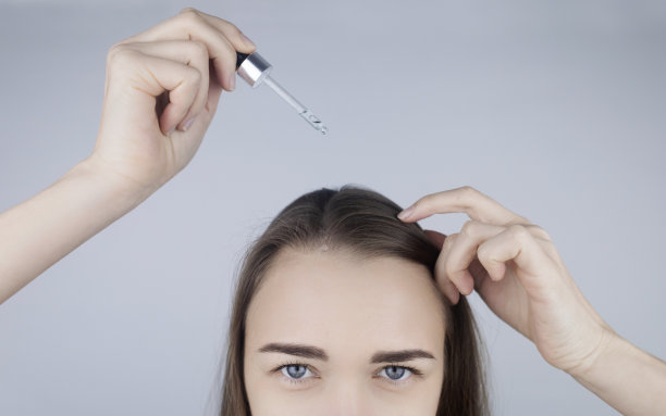 黑发女孩用油在她的头上加强发根和护理她的头发。防止秃顶，脆性，褪色，褪色，头发加强。护理和美容的概念图片下载