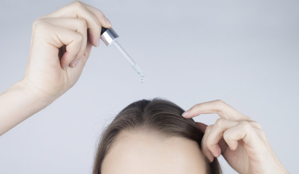 黑发女孩用油在她的头上加强发根和护理她的头发。防止秃顶，脆性，褪色，褪色，头发加强。护理和美容的概念图片下载