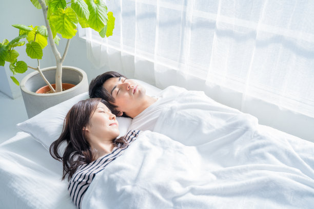 一对年轻夫妇睡在卧室的床上。图片下载