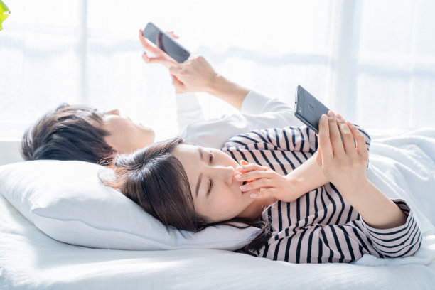 情侣在床上看智能手机。图片下载