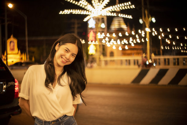美丽的年轻女子微笑着，在城市的彩灯花环，圣诞快乐图片下载