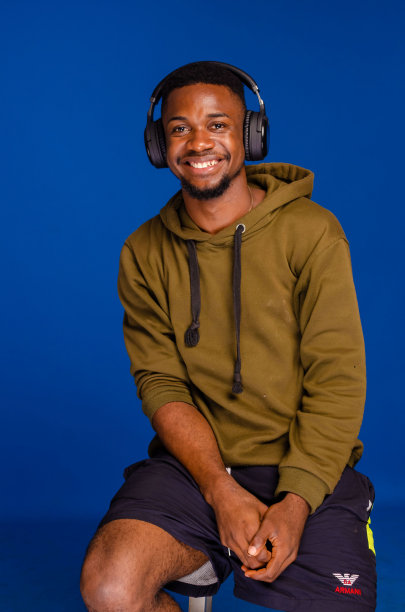 一个微笑的年轻非洲男子的垂直特写，耳机孤立在蓝色背景上。图片下载