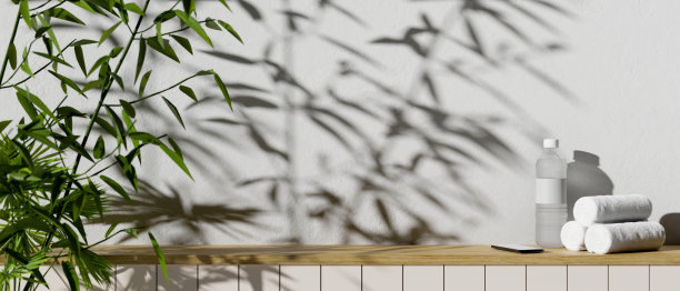 一瓶水、毛巾、智能手机和复印空间放在一张靠白墙的小木桌上图片下载