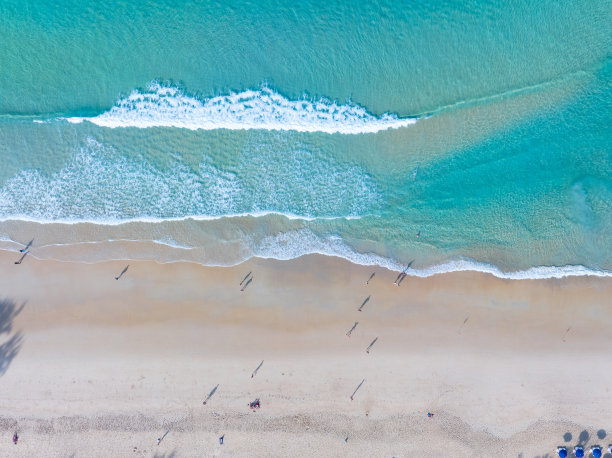 美丽的海浪水面，沙滩沙滩海岸和波浪白色泡沫夏日阳光明媚的日子背景。令人惊叹的海滩自上而下俯瞰海滨自然背景图片下载