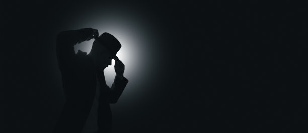 那人把帽子戴在头上。背景光源图片下载