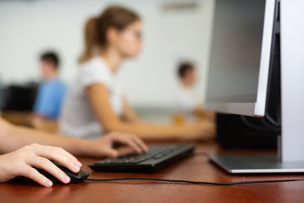 模糊的照片，女青少年戴着眼镜学习计算机科学，而她正在计算机教室里使用PC图片下载