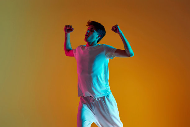 在黄色背景上跳舞的男人。霓虹灯照明图片下载