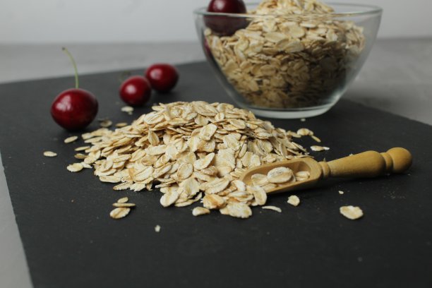 燕麦片放在黑色托盘上，杯子放在玻璃碗里，旁边是樱桃浆果。滚筒食品avtrak。自制的烹饪图片下载