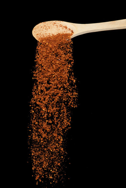 红辣椒落下，红粒辣椒炸出抽象的云从木勺里飞出来。漂亮完整的种寒、食物设计。选择性聚焦冻结拍摄黑色背景隔离图片下载