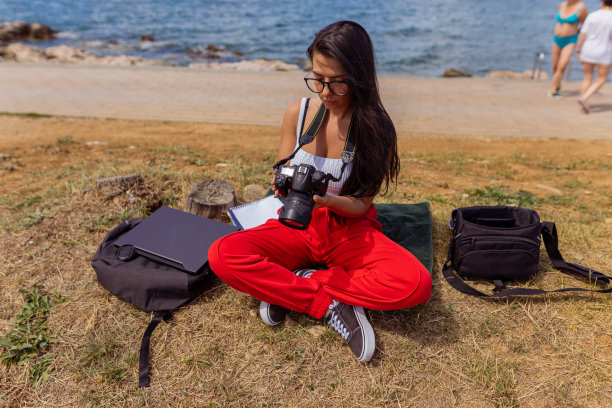 海滩上一个拿着相机的年轻女子图片下载
