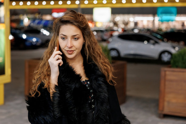 年轻开朗的女人在晚上走在城市里打电话图片下载