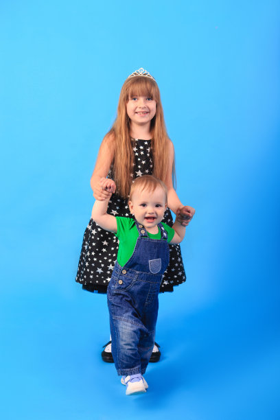 一个女孩牵着男孩的手，背景是蓝色的。图片下载