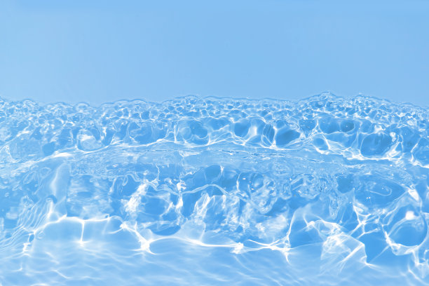 离焦模糊透明蓝色颜色清晰平静的水面纹理与飞溅和气泡。潮流抽象的自然背景。水波在阳光下带有焦散。碧水闪耀图片下载