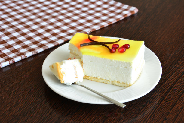 柑橘芝士蛋糕切片，用茶匙放在白色碟子上图片下载