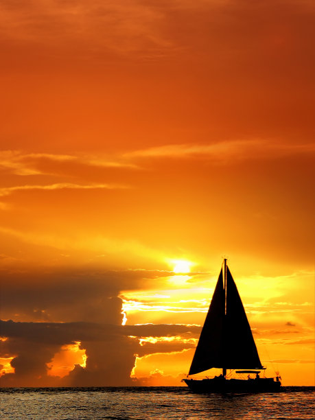 剪影帆船漂浮在橙色的海景在戏剧性的日落天空图片下载