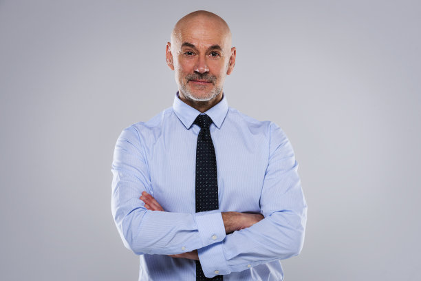 微笑成熟的男性CEO，双臂交叉站在孤立的背景图片下载