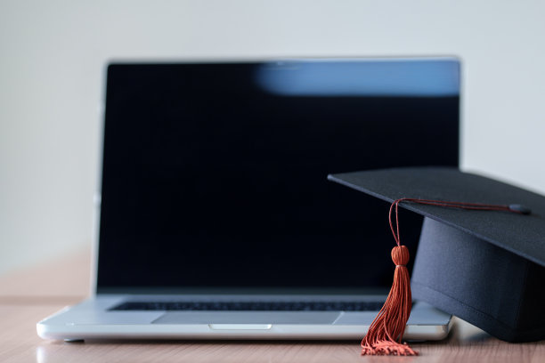 毕业帽与笔记本电脑步伐在木桌背景。图片下载