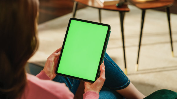 女性在平板电脑上滚动和点击内容，绿色屏幕模拟显示。女人在家放松，在移动设备上阅读社交媒体帖子。近距离拍摄肩部照片。图片下载