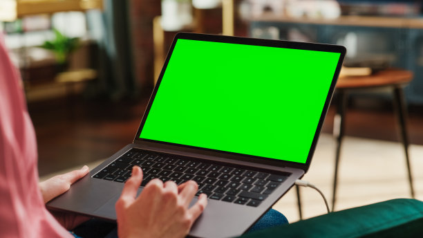 年轻的成年妇女在带绿色屏幕模拟显示器的笔记本电脑上从家庭阁楼公寓工作。创意女性使用触控板和浏览互联网。近距离拍摄肩部照片。图片下载