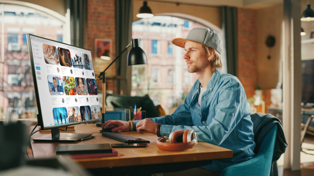 年轻英俊的男子正在观看视频在线流媒体服务。检查社交媒体，浏览互联网，消费网红的内容。从大窗户看城市。图片下载