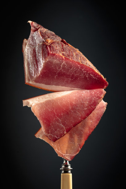 用叉子夹的干腌猪肉片。图片下载