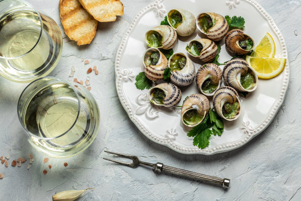 勃艮第蜗牛配香草、黄油、大蒜，一杯白葡萄酒配上清淡的背景，美味佳肴。餐厅菜单，传统的法国菜图片下载