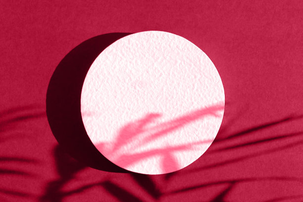 抽象的最小场景的几何形式。一个圆柱形的白色讲台上的洋红色背景与热带棕榈叶的阴影。展示化妆品产品的场景。陈列柜，展示柜。图片下载