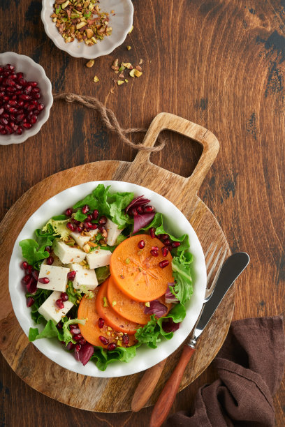 沙拉。新鲜蔬菜沙拉配羊乳酪，柿子，石榴和开心果，白盘子。健康美味的冬季圣诞沙拉。健康均衡的饮食。前视图。图片下载