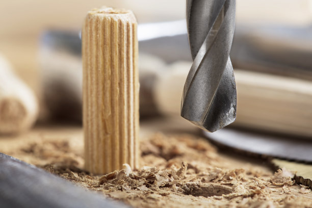 钻头在橡木木板上钻孔，用于木销子。图片下载