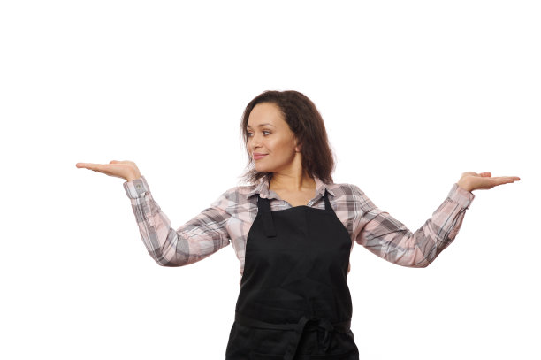 可爱的漂亮的黑发穿着黑色的厨师围裙，微笑着看着拷贝空间她的双手手掌向上图片下载