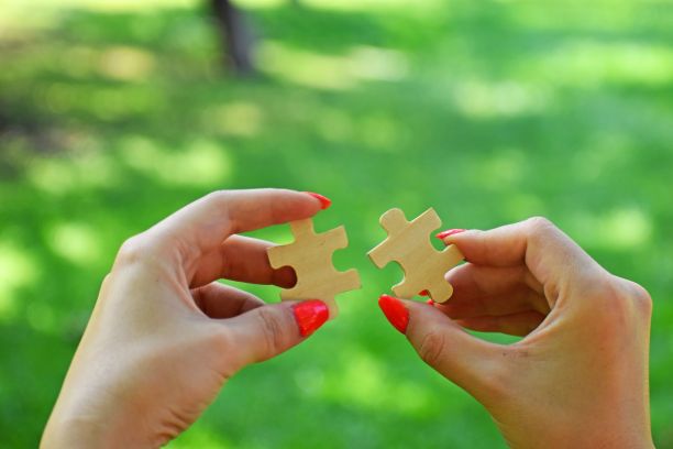 女人的手连接拼图碎片上的自然背景-商业战略的概念图片下载