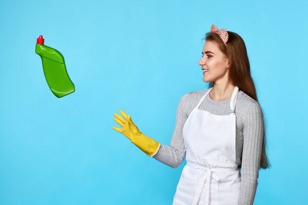 戴橡胶手套的女人接住飞起的清洁剂瓶子图片下载
