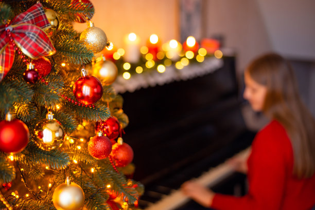 装饰明亮的冷杉树和年轻的女孩弹钢琴的背景图片下载
