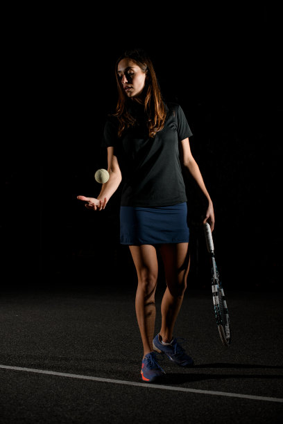 女网球运动员手持网球拍，将网球向上抛起图片下载