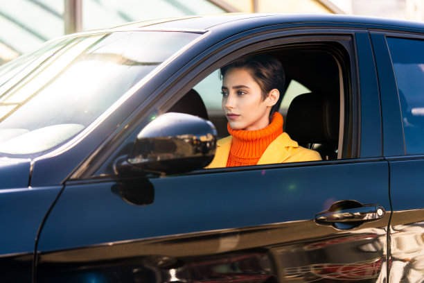 年轻漂亮的短发女子在城市里开车图片下载